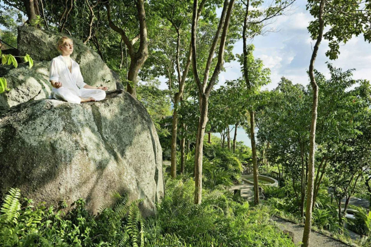 kamalaya koh samui solo wellness retreat woman meditating on rock